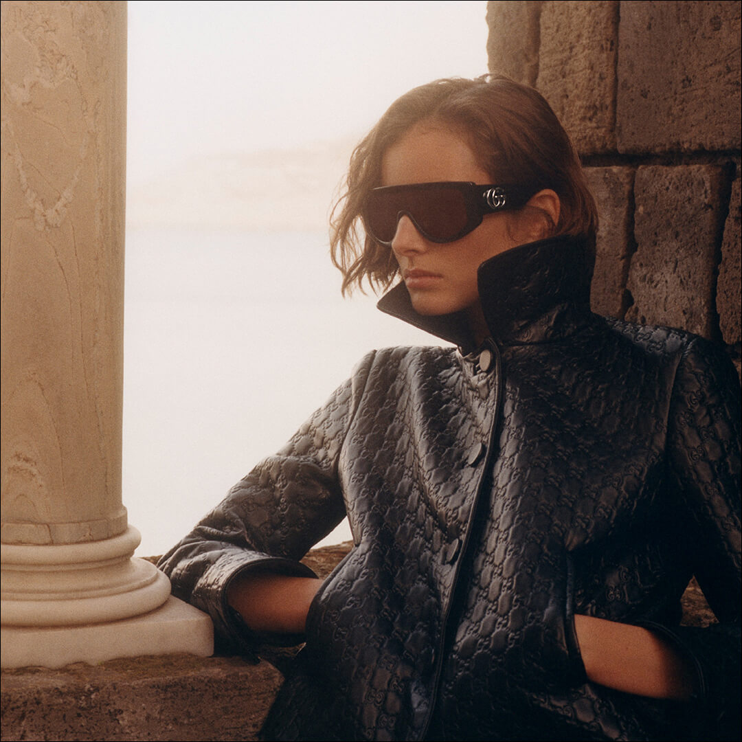 Woman wearing Gucci sunglasses and a dark coat