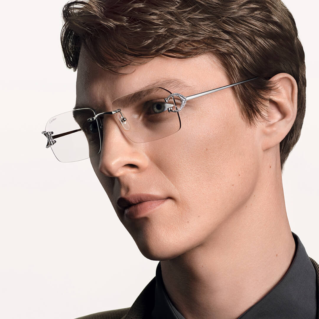 Close-up of a person wearing Cartier Precious rimless eyeglasses with a neutral background